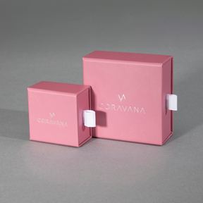 Two pink boxes with the brand name 'CORAVANA' on them, one larger box contains a smaller box, against a grey background.