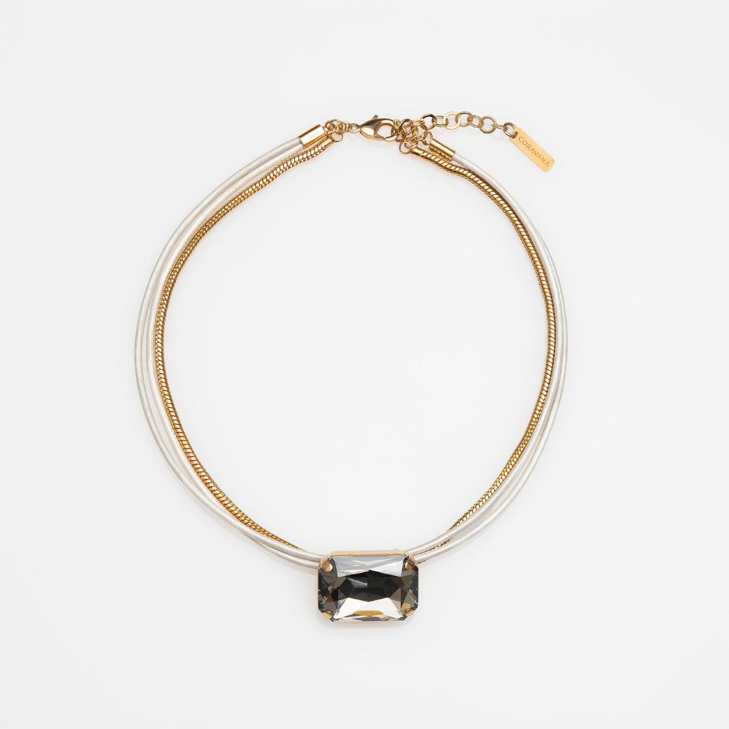 A choker necklace with a gold chain and silver leather layers, featuring an octagon-shaped pink crystal centerpiece.