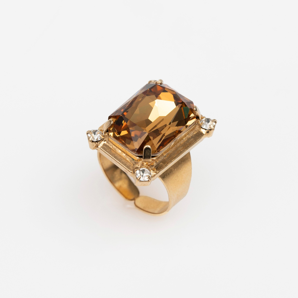 A golden ring with an emerald cut crystal centerpiece and small crystals adorning the band.