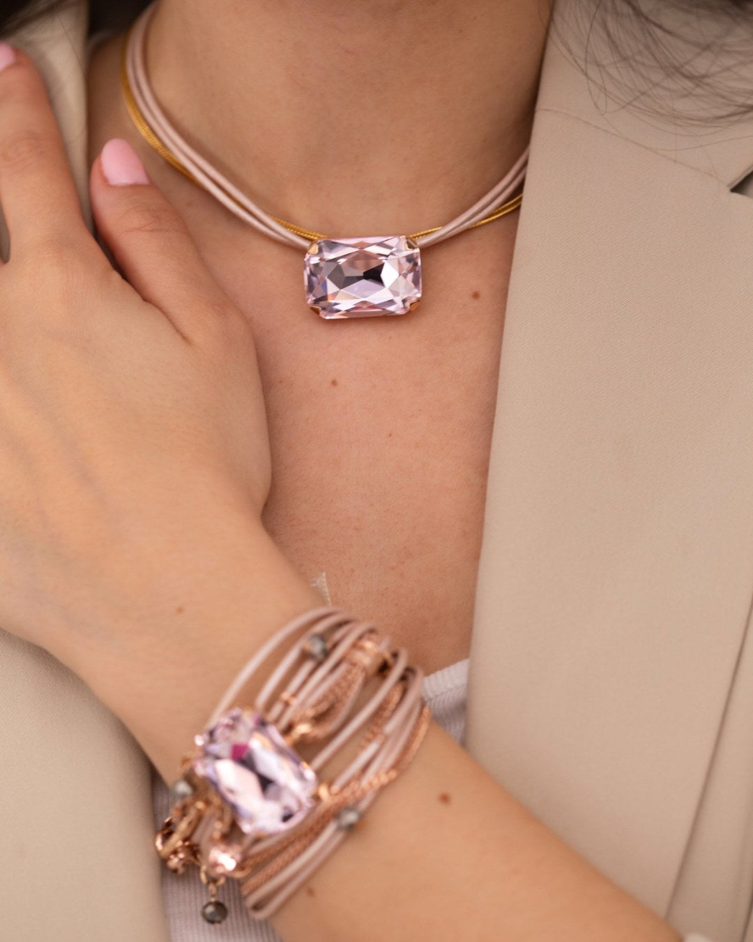 Close-up of a person wearing a pink gemstone bracelet and necklace.