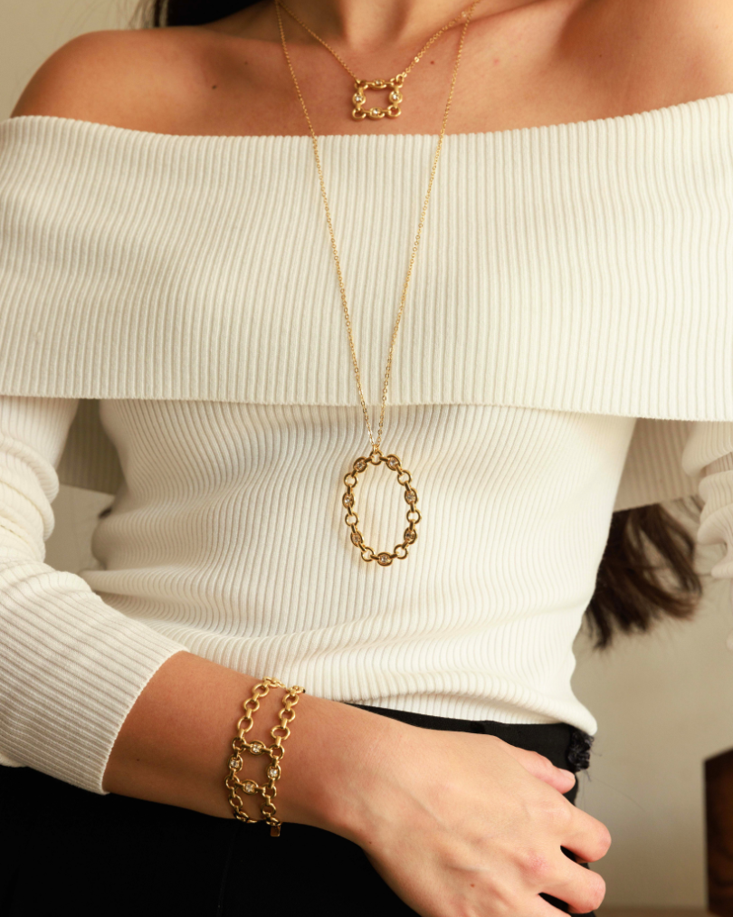Person wearing a gold necklace and bracelet on a white background