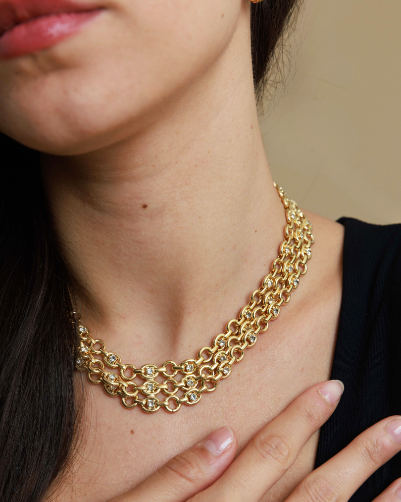 Gold chain necklace worn by a person with a blurred background