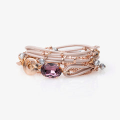 A pink Stargaze bracelet with an oval-shaped crystal centerpiece and small glass beads, featuring a gold-tone chain.