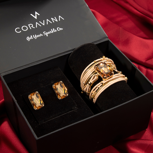 Gold jewelry set in a Coravana box on a red fabric background