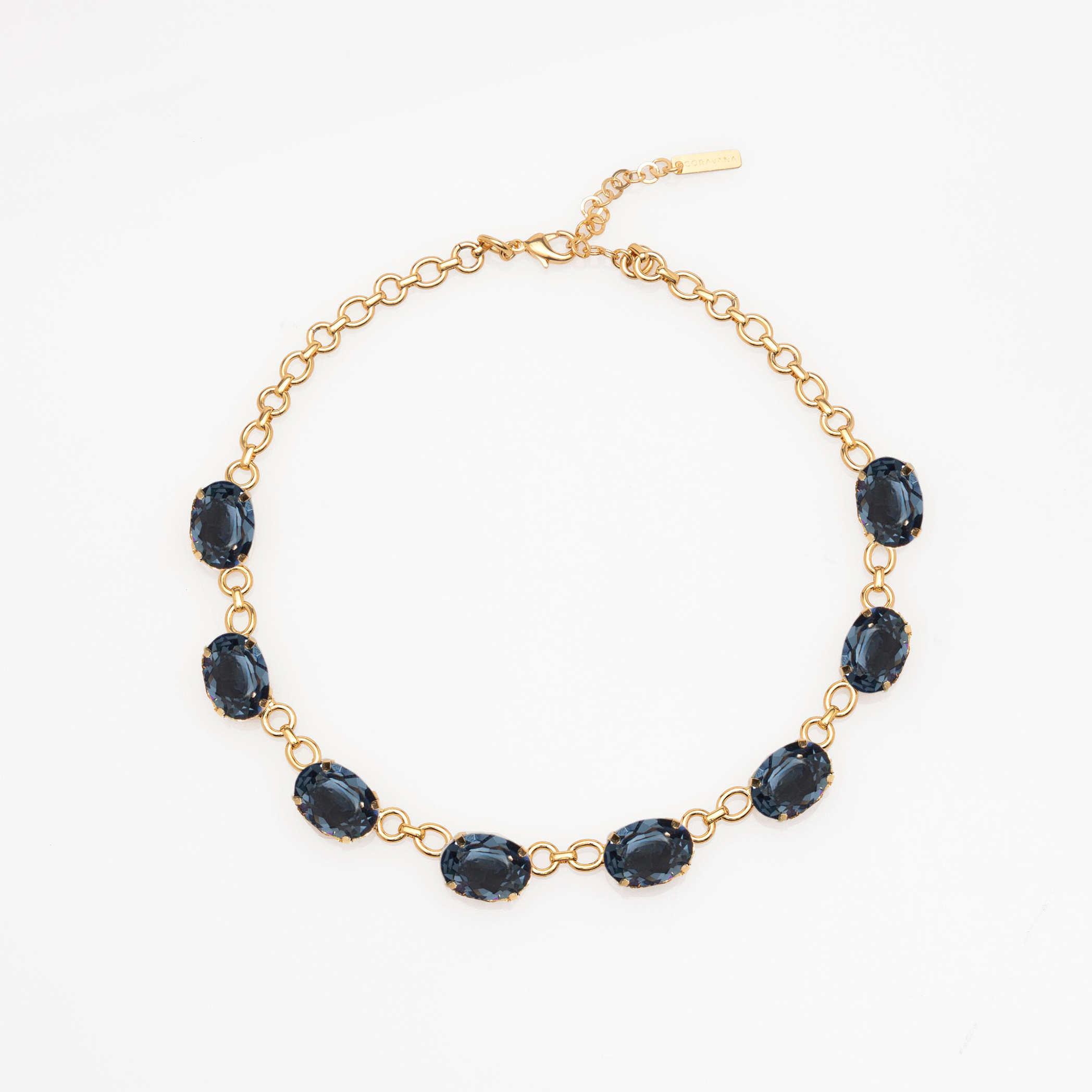 Gold bracelet with dark blue gemstones on a white background