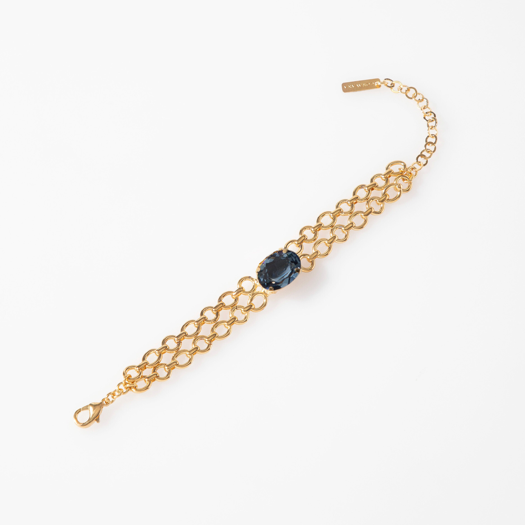 Gold chain bracelet with a blue gemstone on a white background