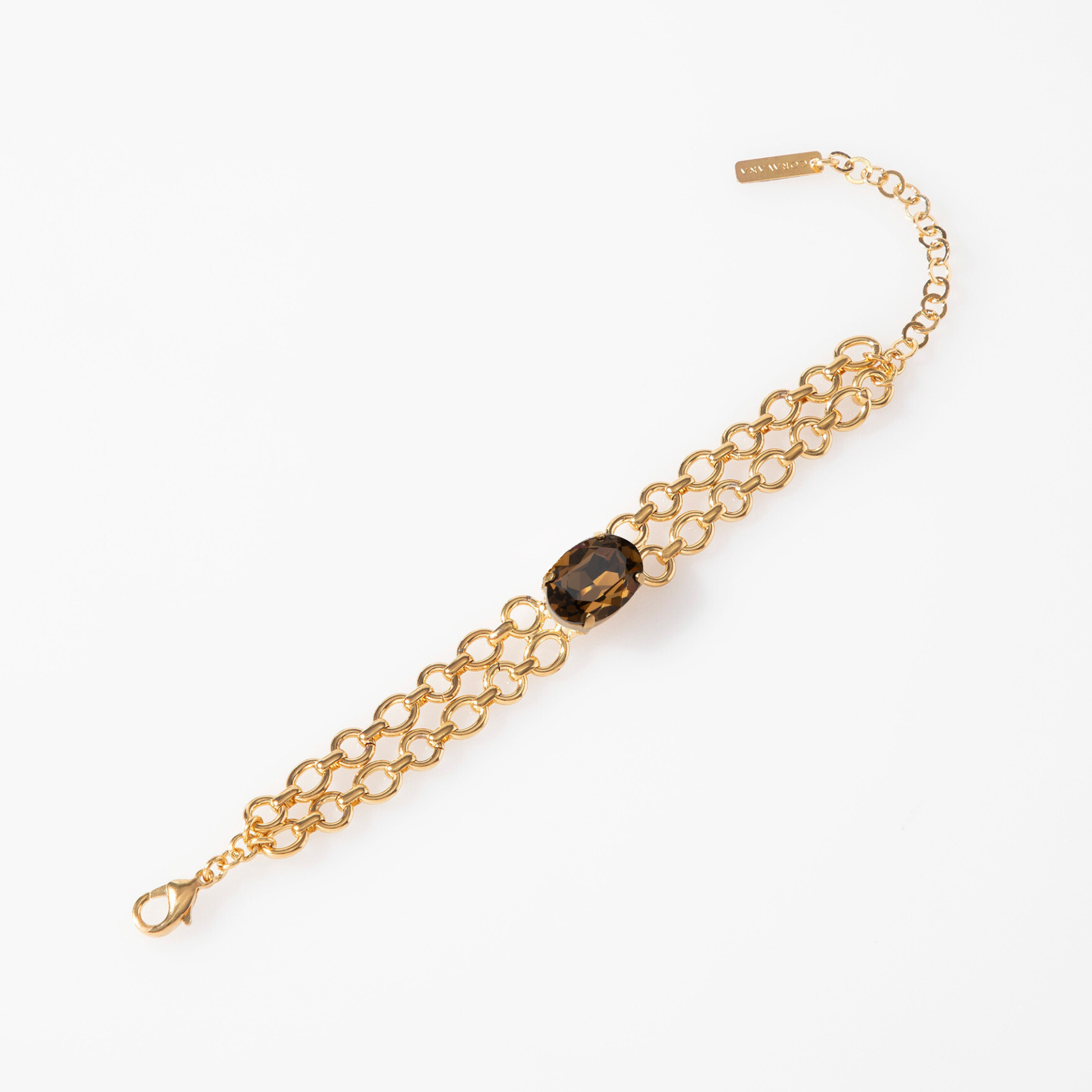 Gold chain bracelet with a dark gemstone on a white background