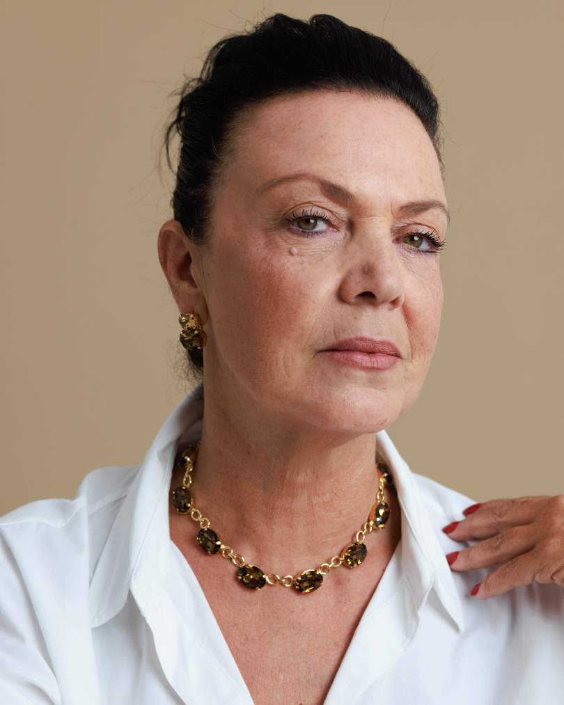 Woman wearing a gold necklace against a beige background