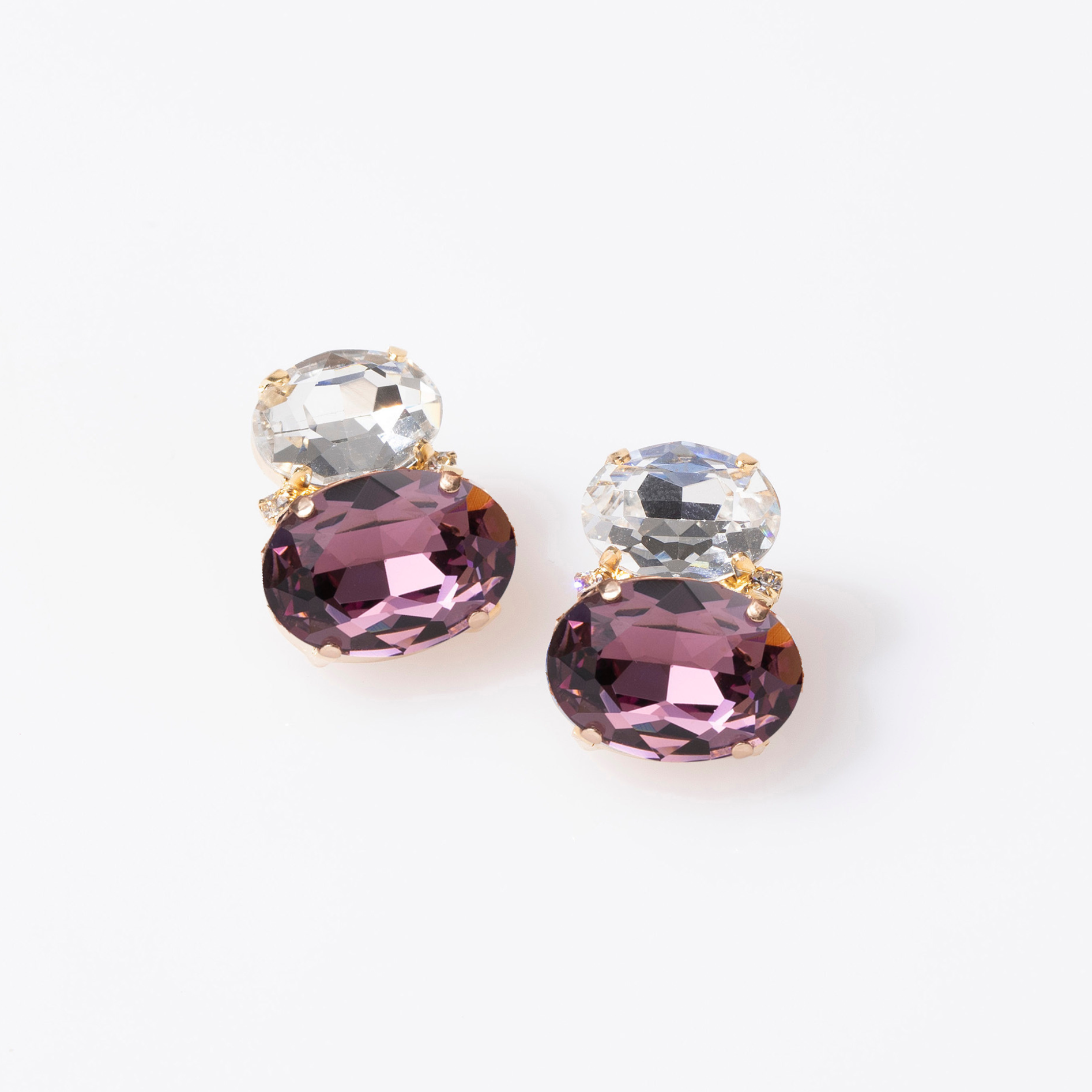 Pair of earrings with purple and clear gemstones on a white background