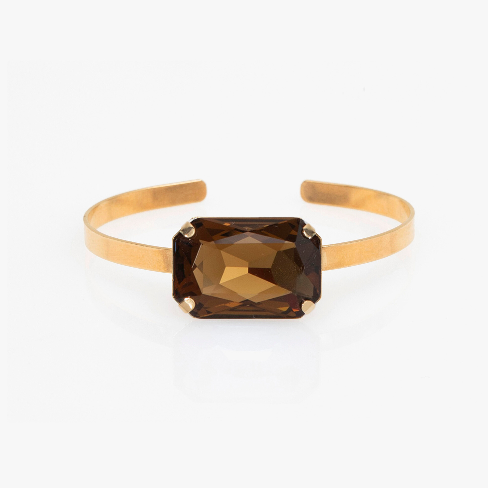 Gold bracelet with a brown gemstone on a white background