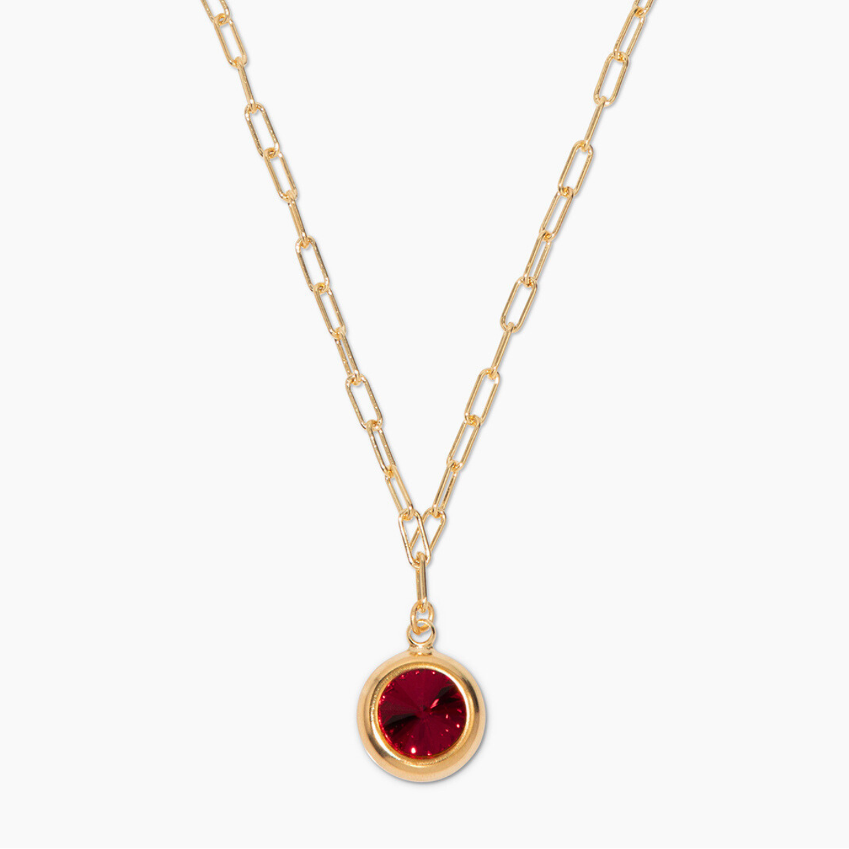 Gold necklace with a red gemstone pendant on a white background