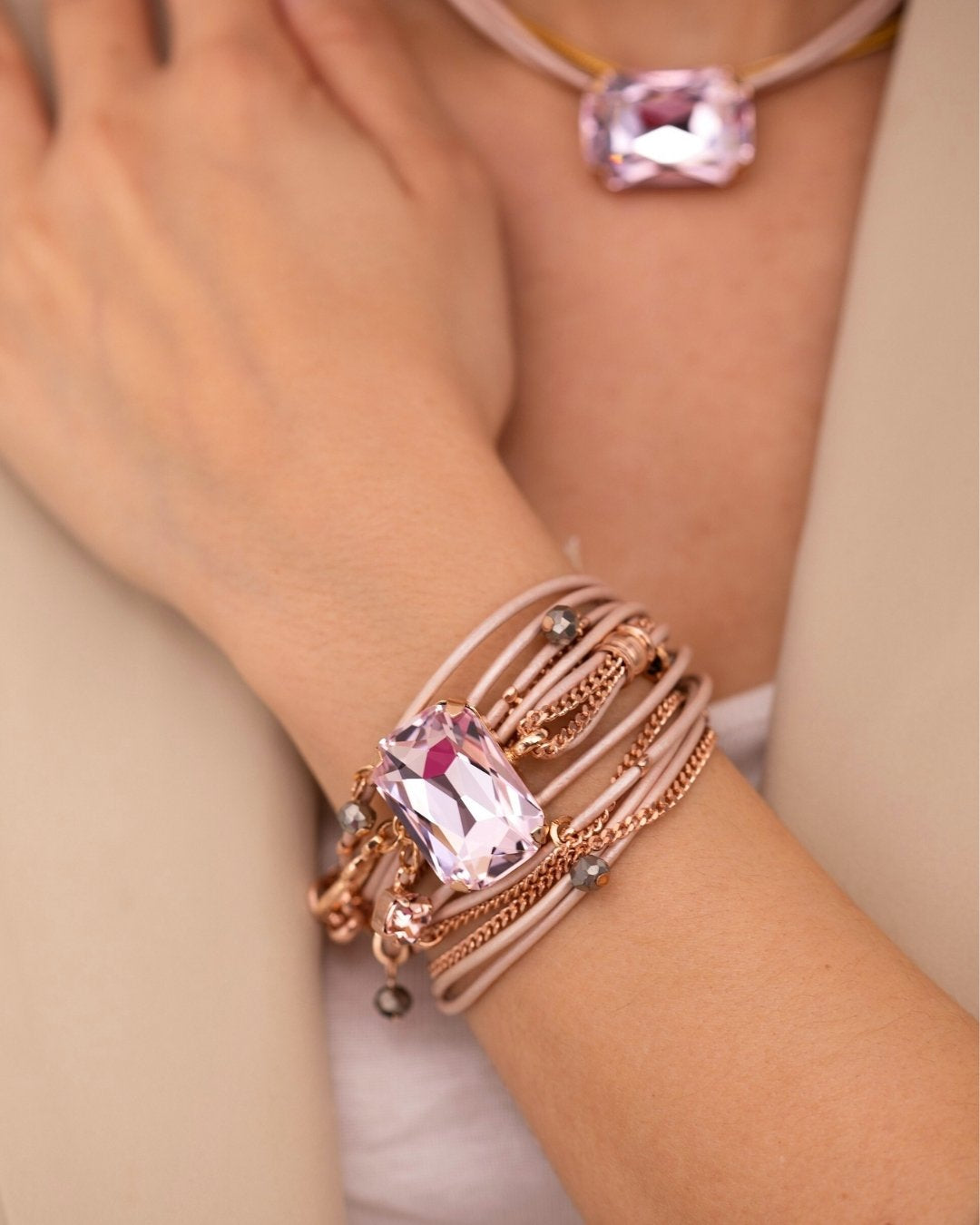 Close-up of a wrist wearing a rose gold bracelet with pink gemstones.