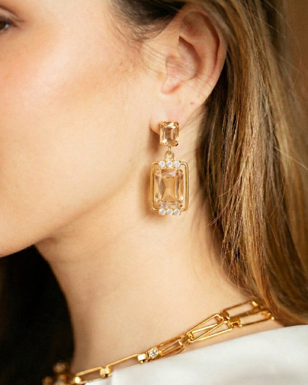 Close-up of a person wearing gold earrings and a necklace from the Spotlight Set