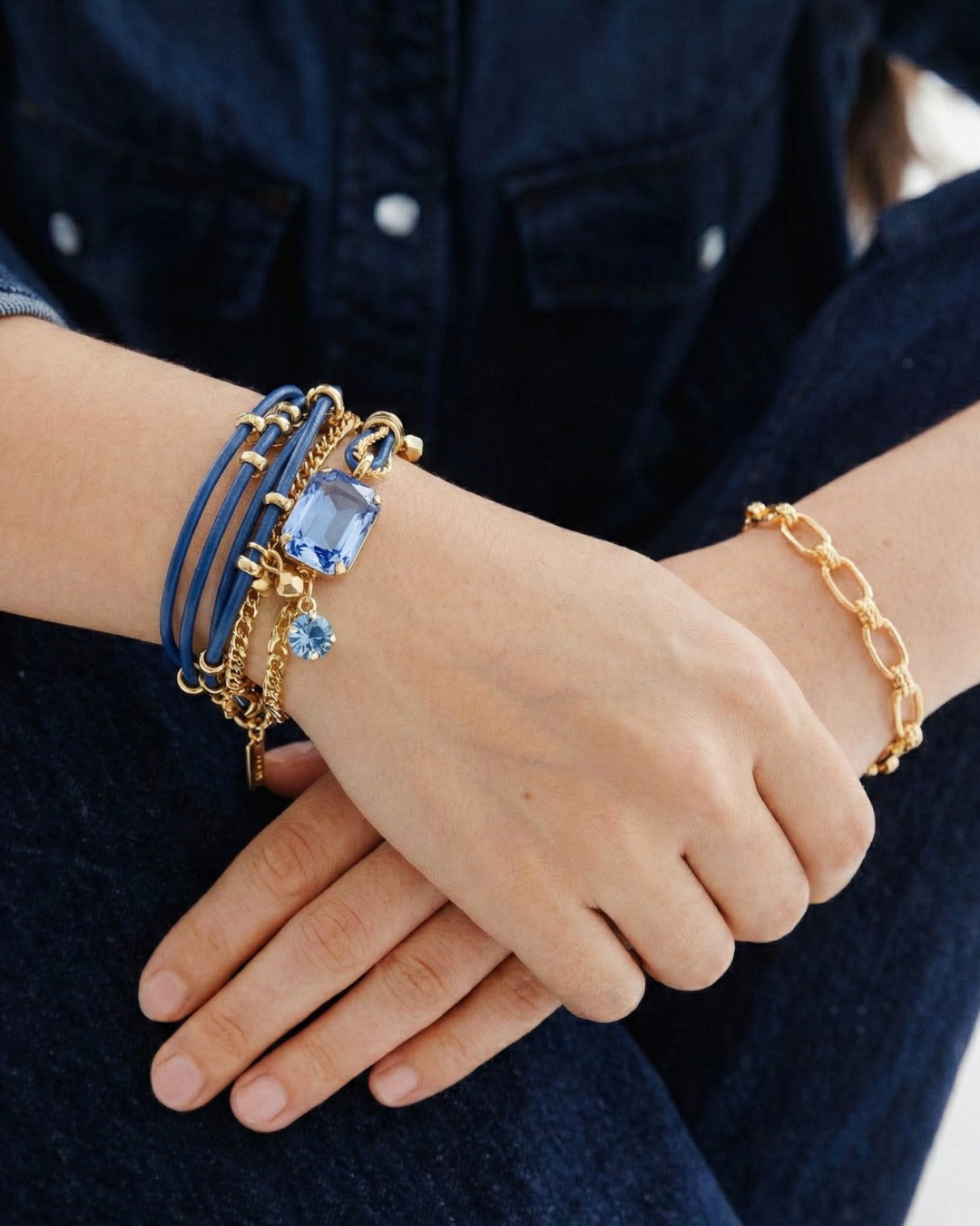 Close-up of a wrist wearing multiple bracelets with blue and gold accents.