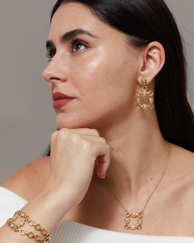 Woman wearing gold hoop earrings and necklace against a neutral background