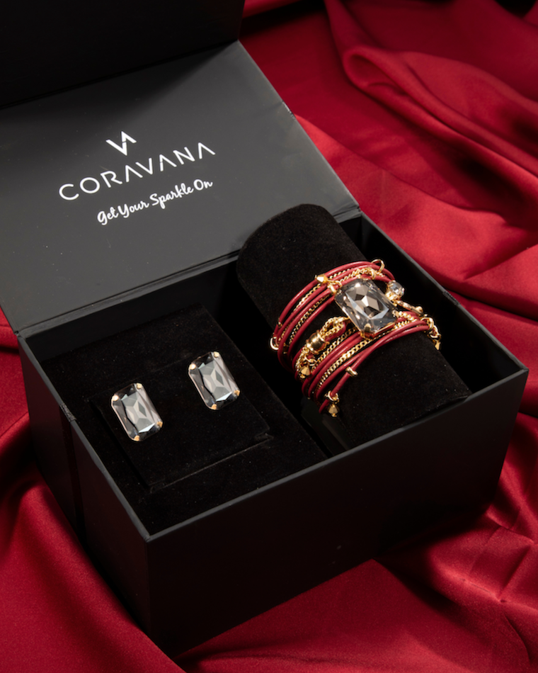 Jewelry set including rings and cufflinks in a Coravana box on a red fabric background
