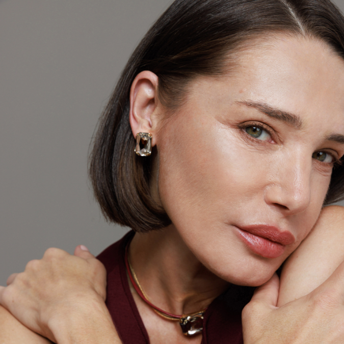 Woman wearing gold jewelry against a neutral background