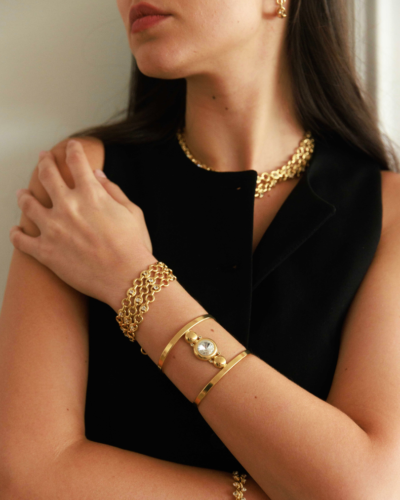 Woman wearing gold jewelry including a necklace, bracelets, and earrings.
