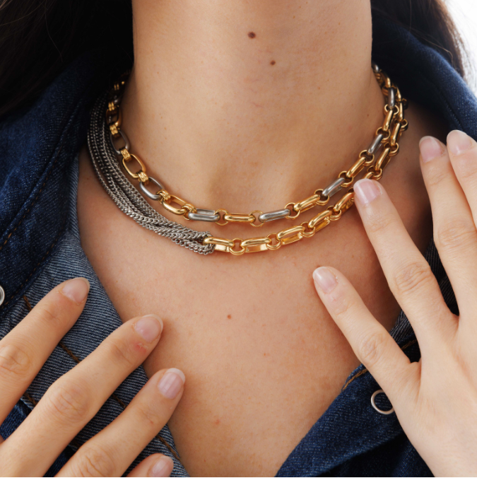 Person wearing a gold chain necklace with a close-up of the necklace and hands.