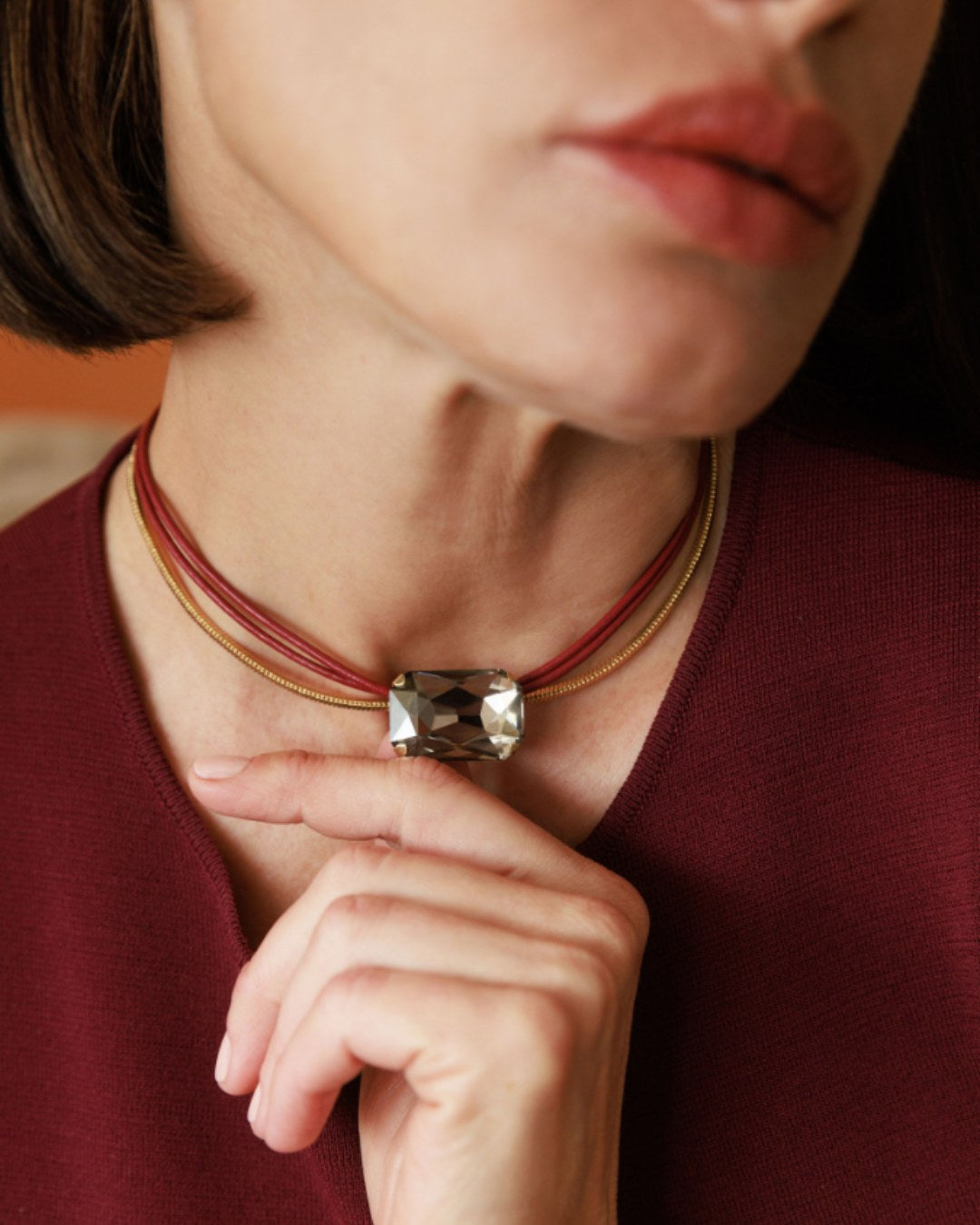 Close-up of a woman wearing a necklace with a prominent gemstone