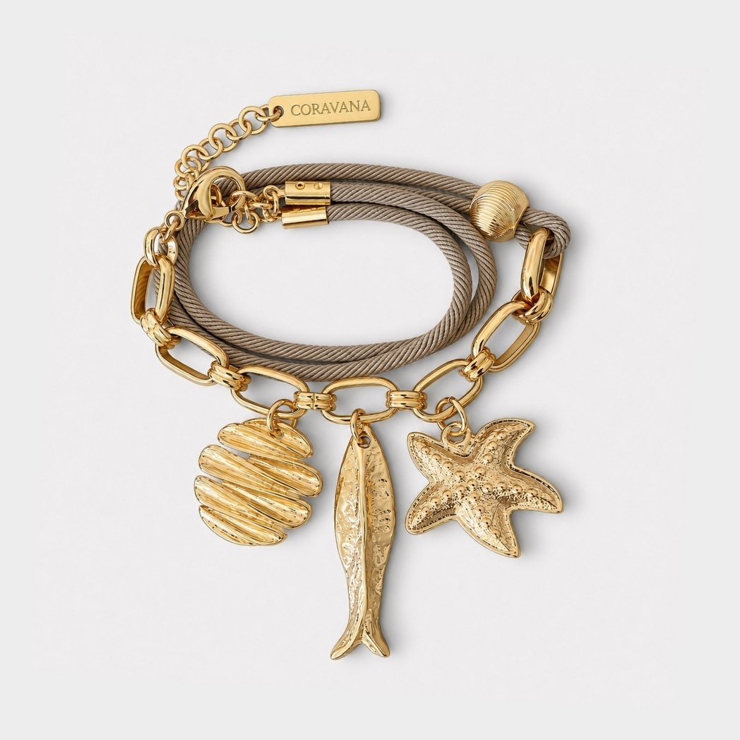 Gold bracelet with shell, fish, and starfish charms on a light gray background