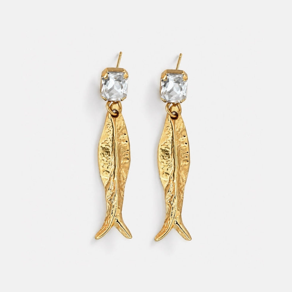 Gold fish-shaped earrings with clear gemstones on a white background