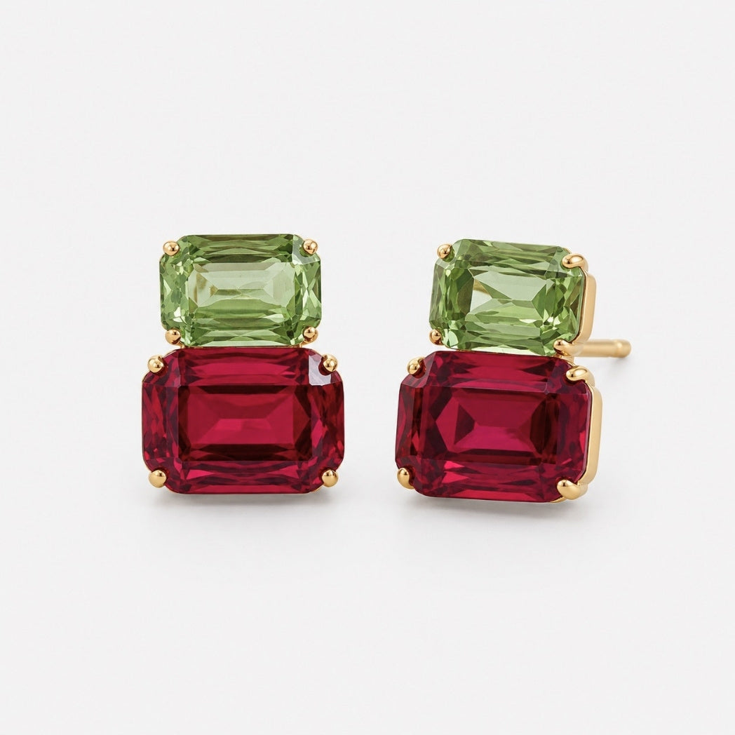A pair of gold stud earrings featuring a stacked design with a green rectangular gemstone on top of a larger red rectangular gemstone, set in gold on a light gray background.