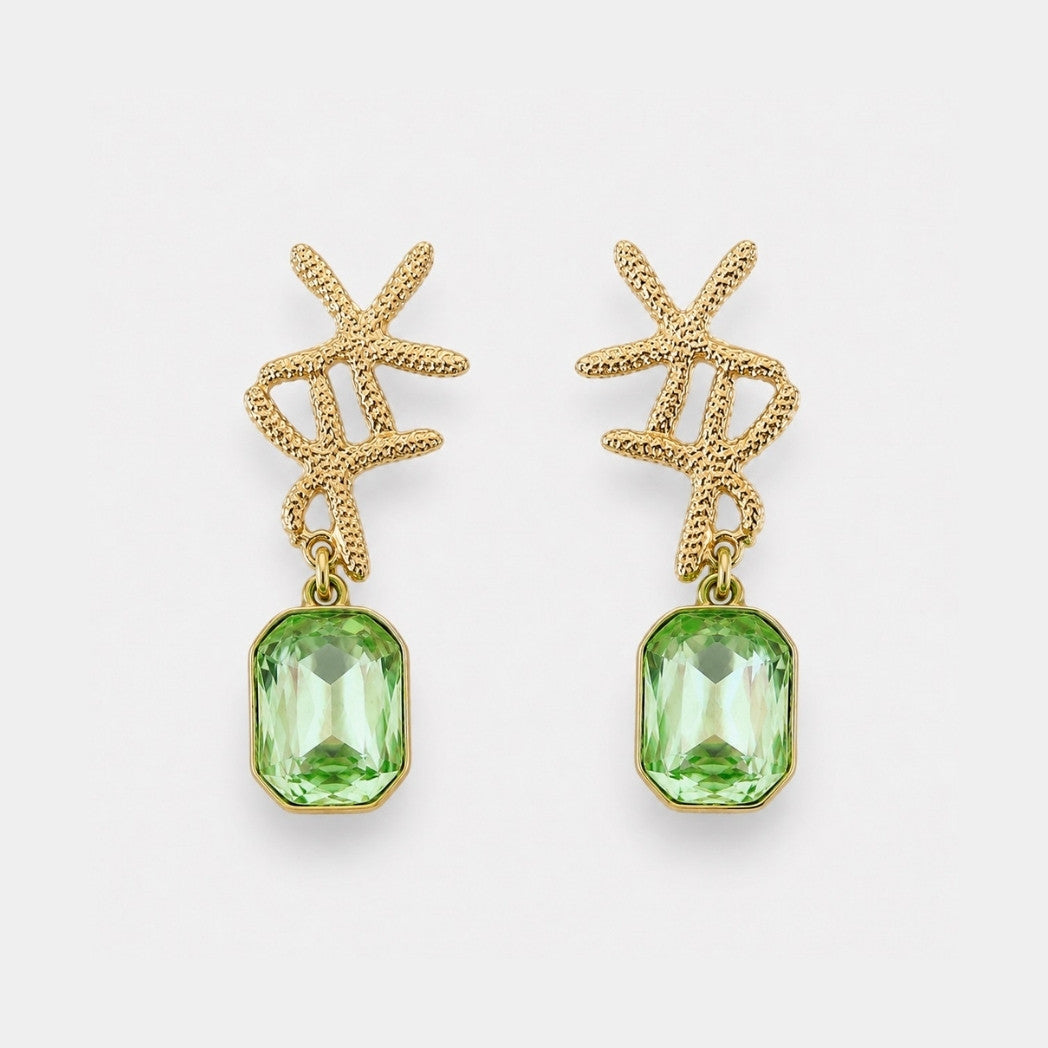 Gold earrings with green gemstones on a white background