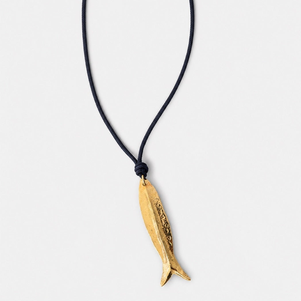 Gold fish-shaped pendant on a black cord against a white background