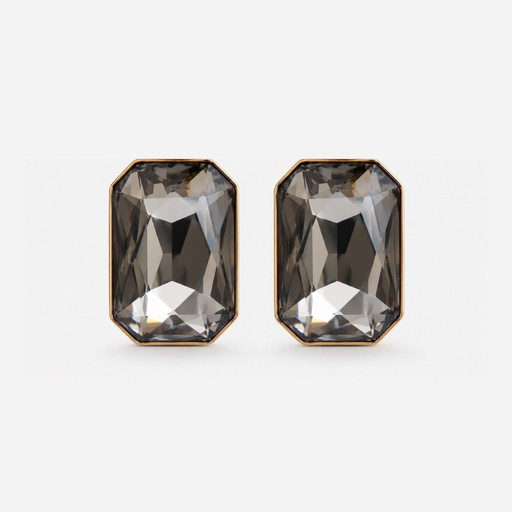 A pair of rectangular faceted smoky gray gemstone stud earrings with gold-toned metal borders, shown on a light gray background.