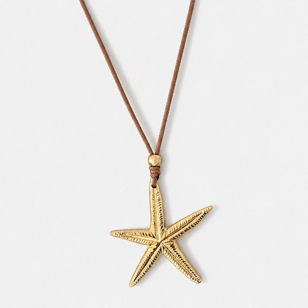 Gold starfish pendant on a brown cord against a white background