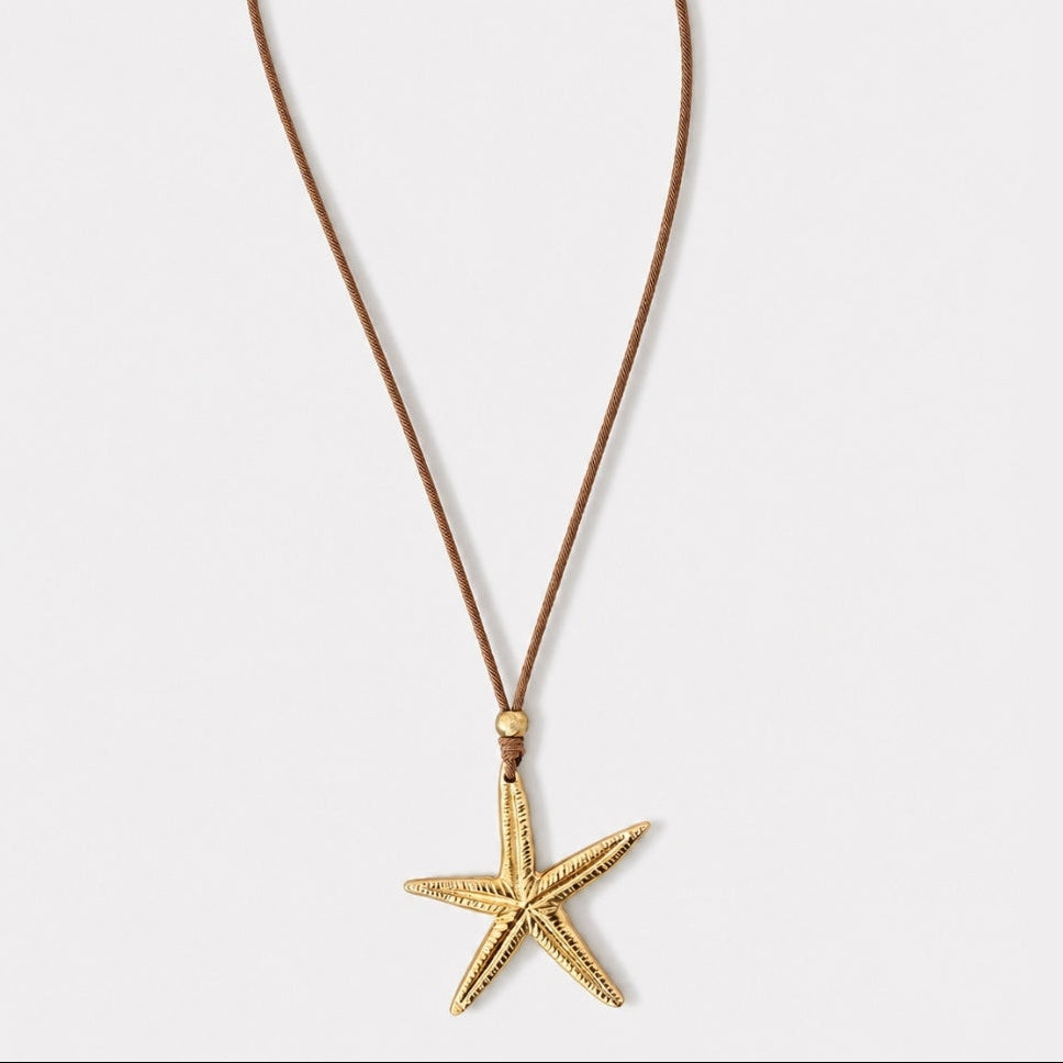 Gold starfish pendant on a brown cord against a white background