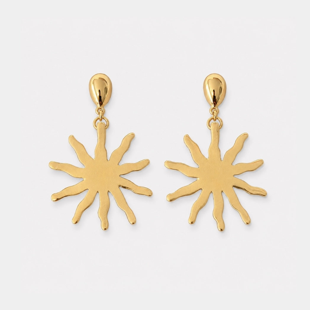 Gold sun-shaped earrings on a white background