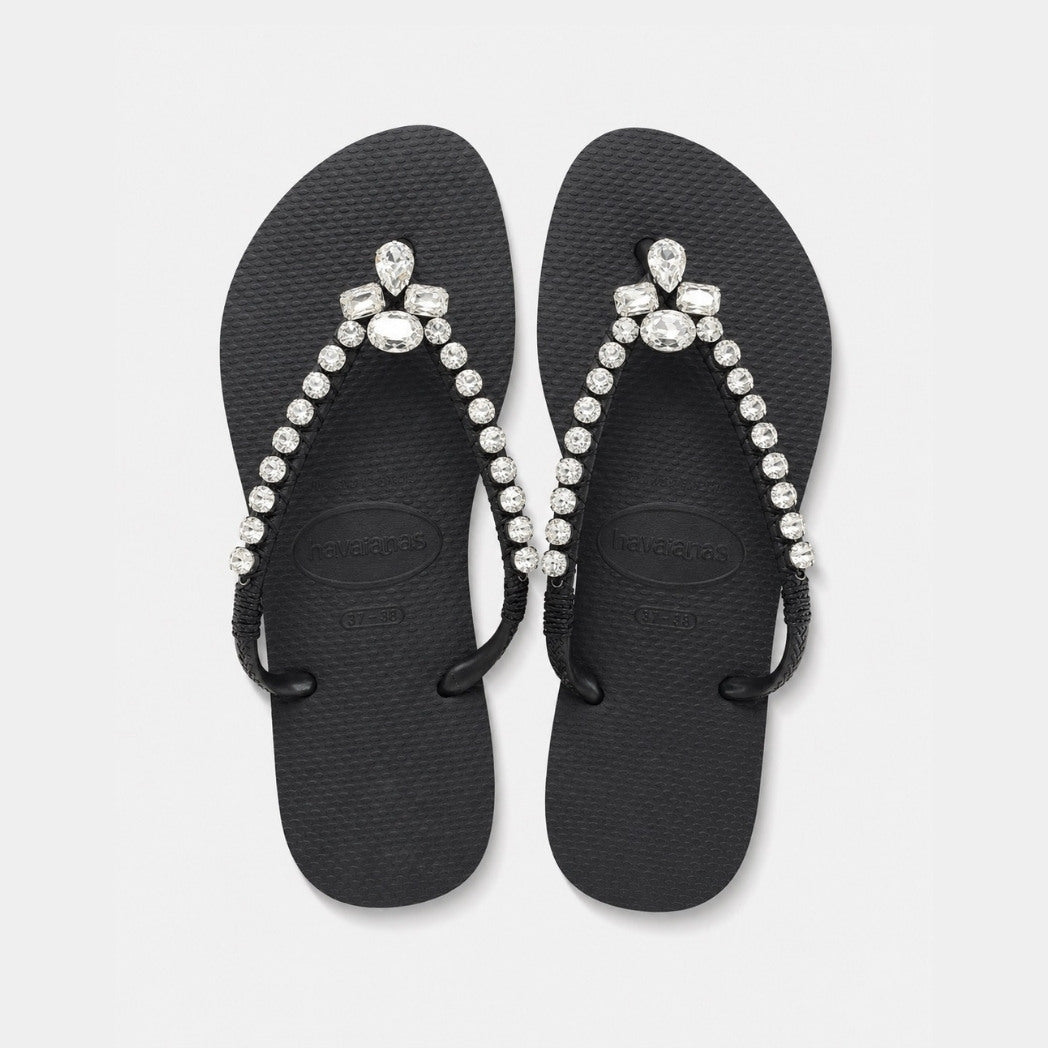 Black flip-flops with pearl and crystal embellishments on a light gray background
