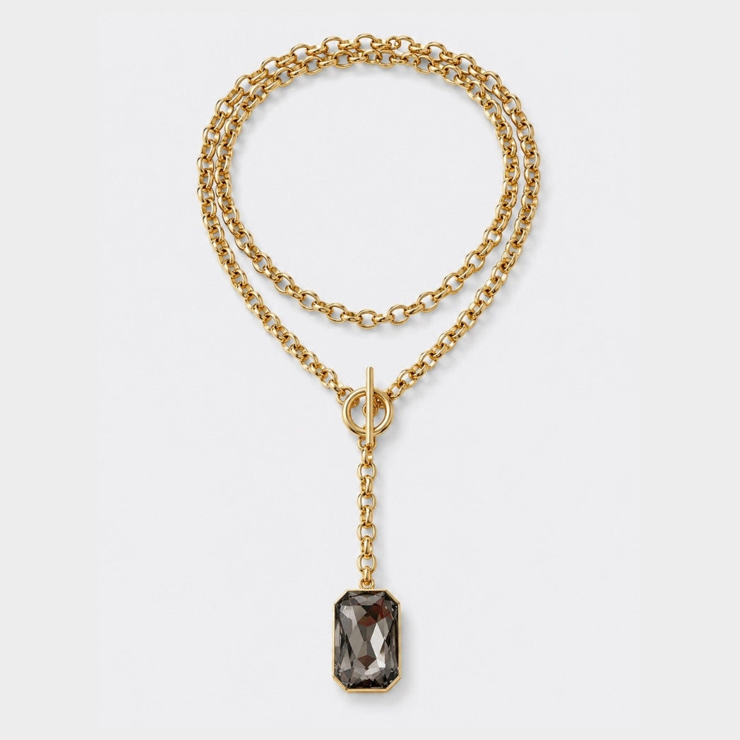 Gold chain necklace with a pendant on a light gray background