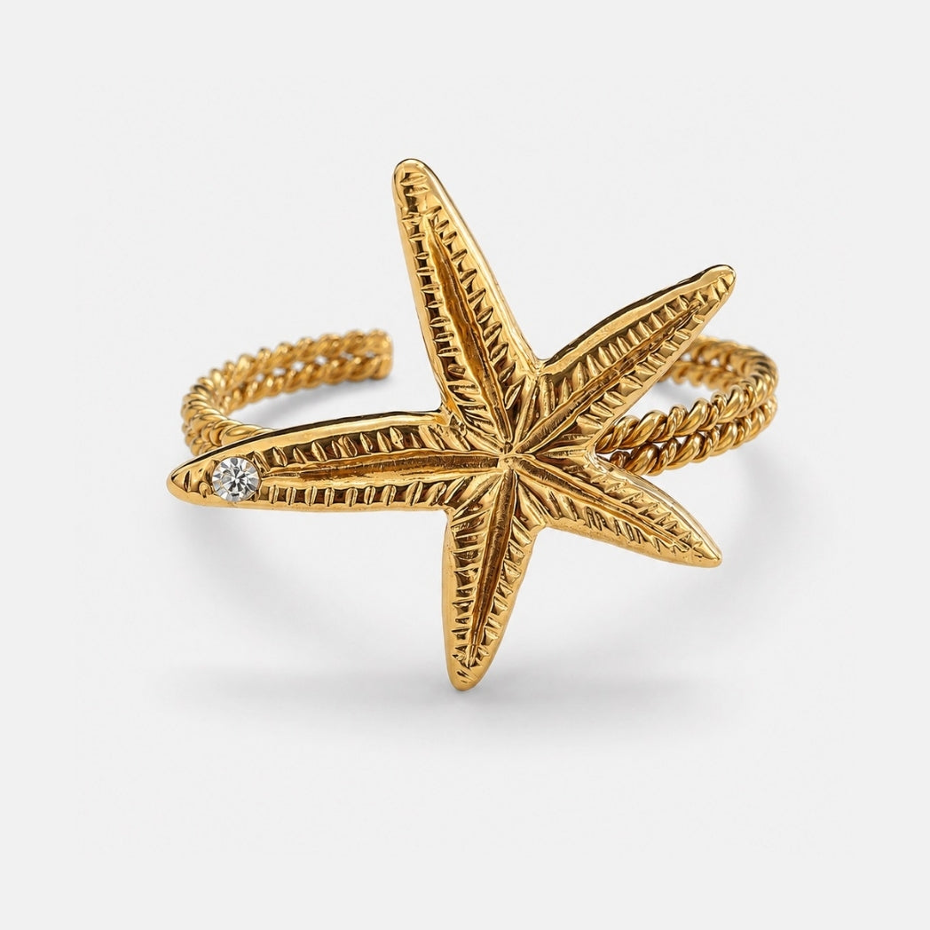 Gold starfish-shaped ring with a diamond on a white background
