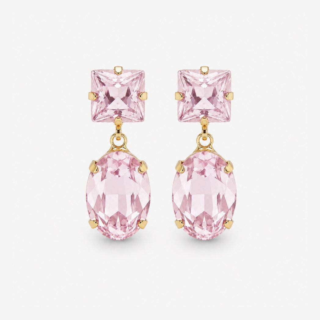 A pair of gold drop earrings featuring a square-cut light pink gemstone on the top and an oval-cut light pink gemstone on the bottom, set against a plain light gray background.