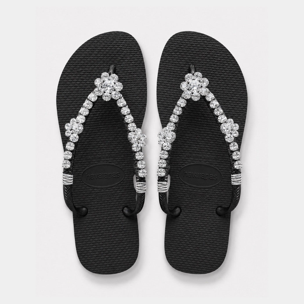 Black flip-flops with crystal embellishments on a light gray background