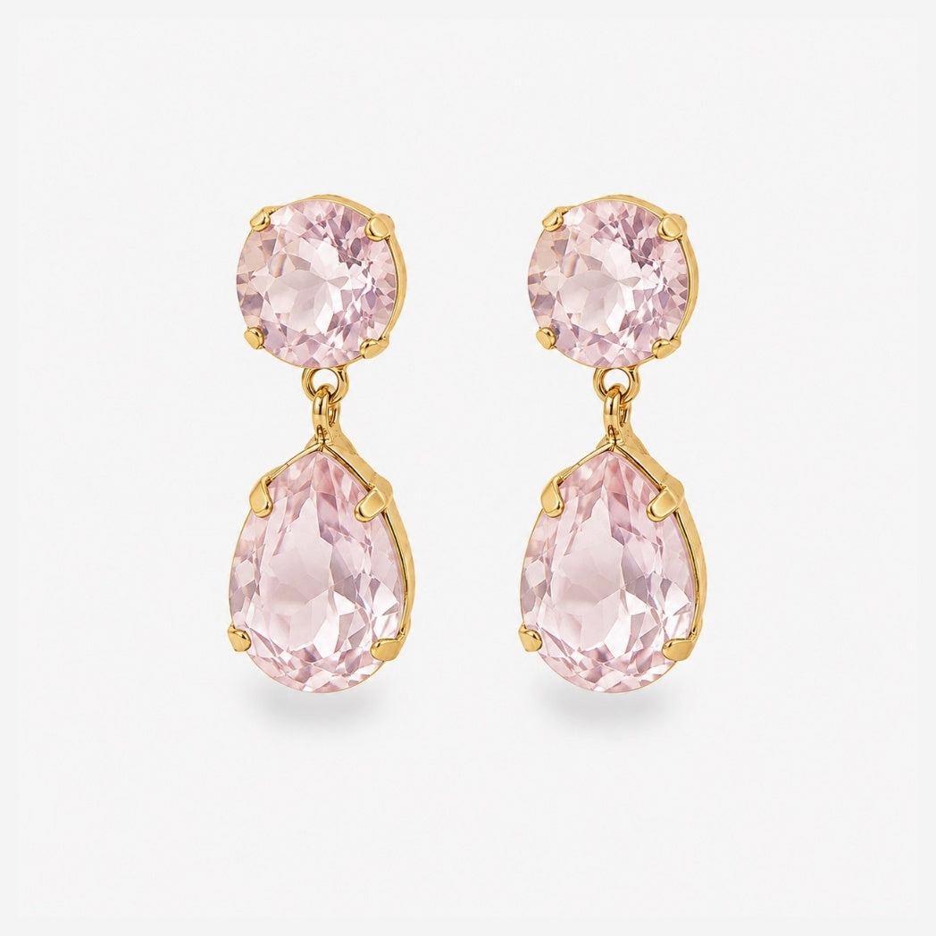 A pair of gold drop earrings featuring a round pink gemstone at the top and a larger teardrop-shaped pink gemstone below, set against a plain light gray background.