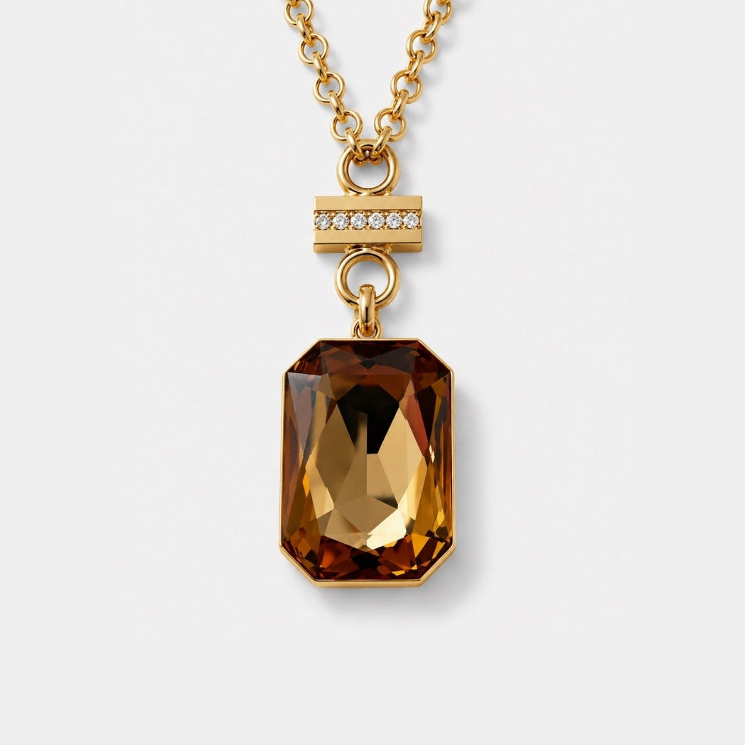 Gold necklace with a large brown gemstone pendant on a light gray background