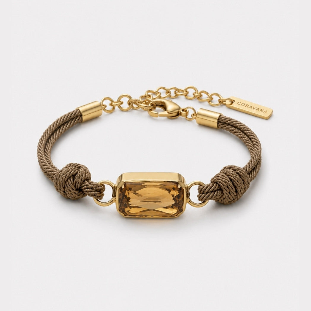 Gold and brown bracelet with a rectangular gemstone on a white background