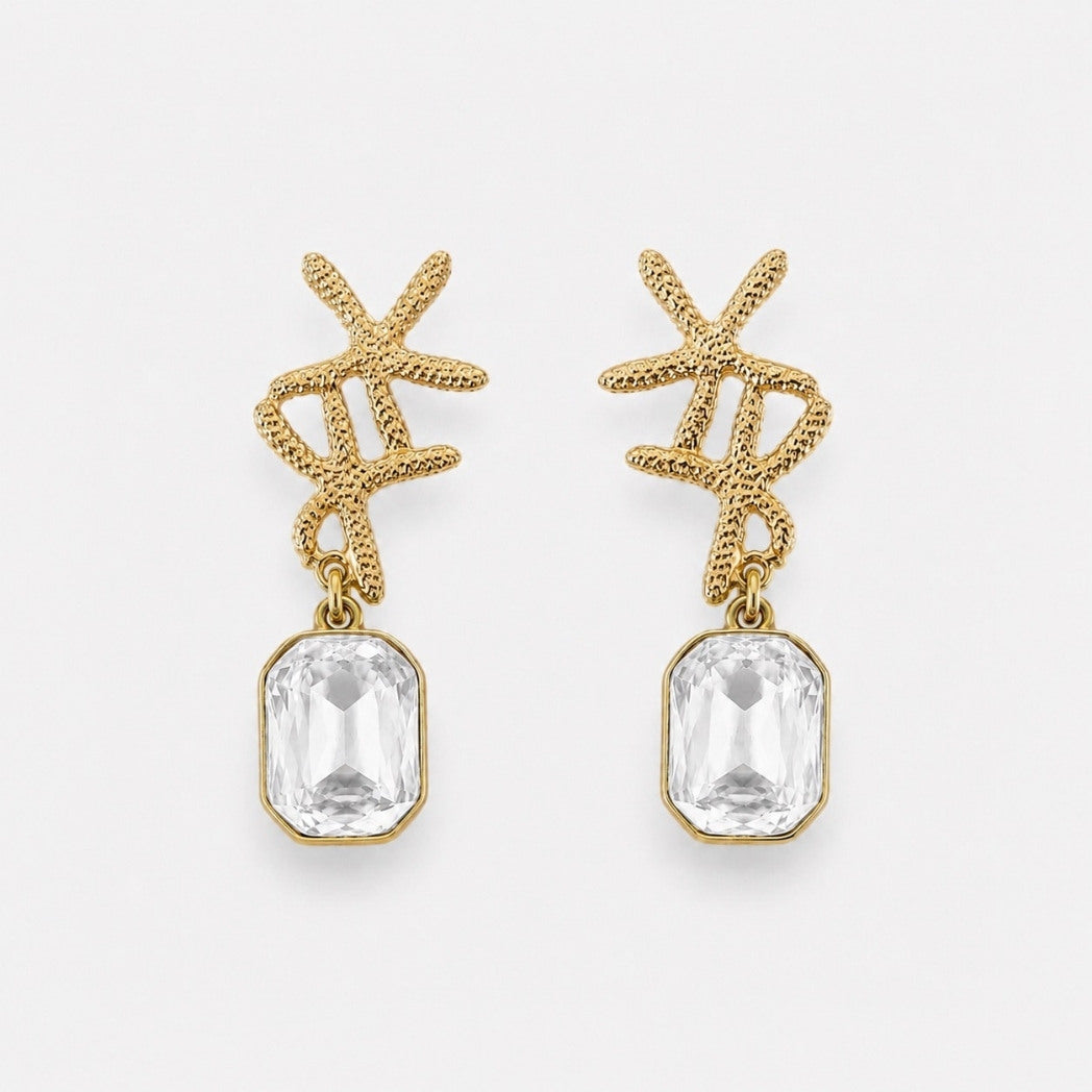 Gold earrings with clear gemstones on a white background