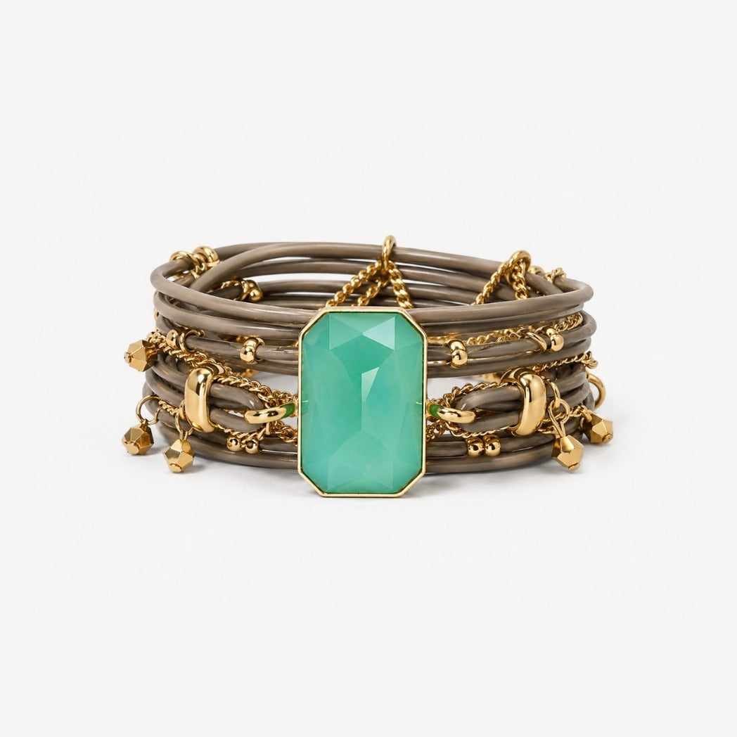 Stack of bracelets with a green gemstone and gold accents on a white background