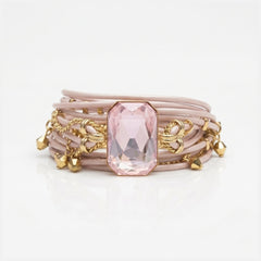 Stack of pink bracelets with gold charms on a white background