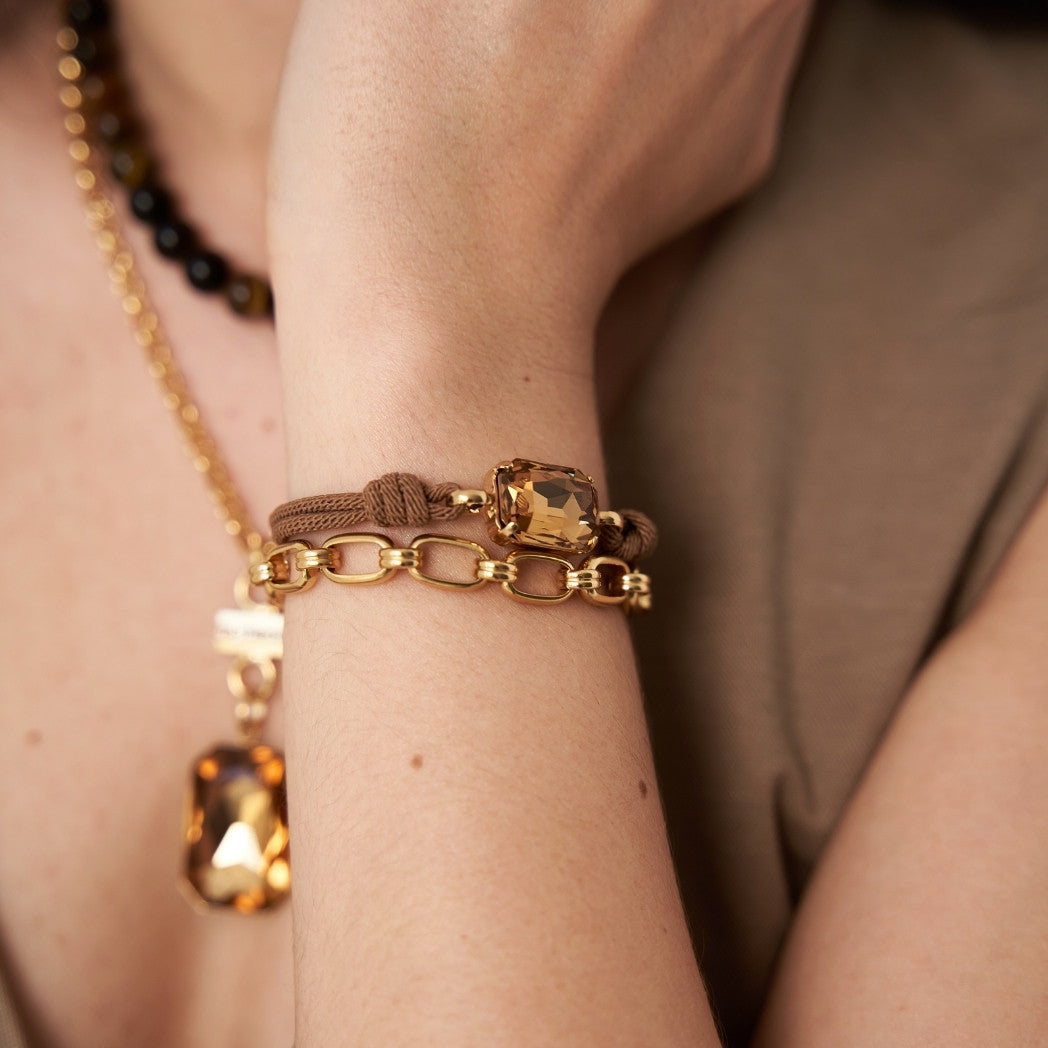 Close-up of a wrist wearing gold bracelets with a neutral background