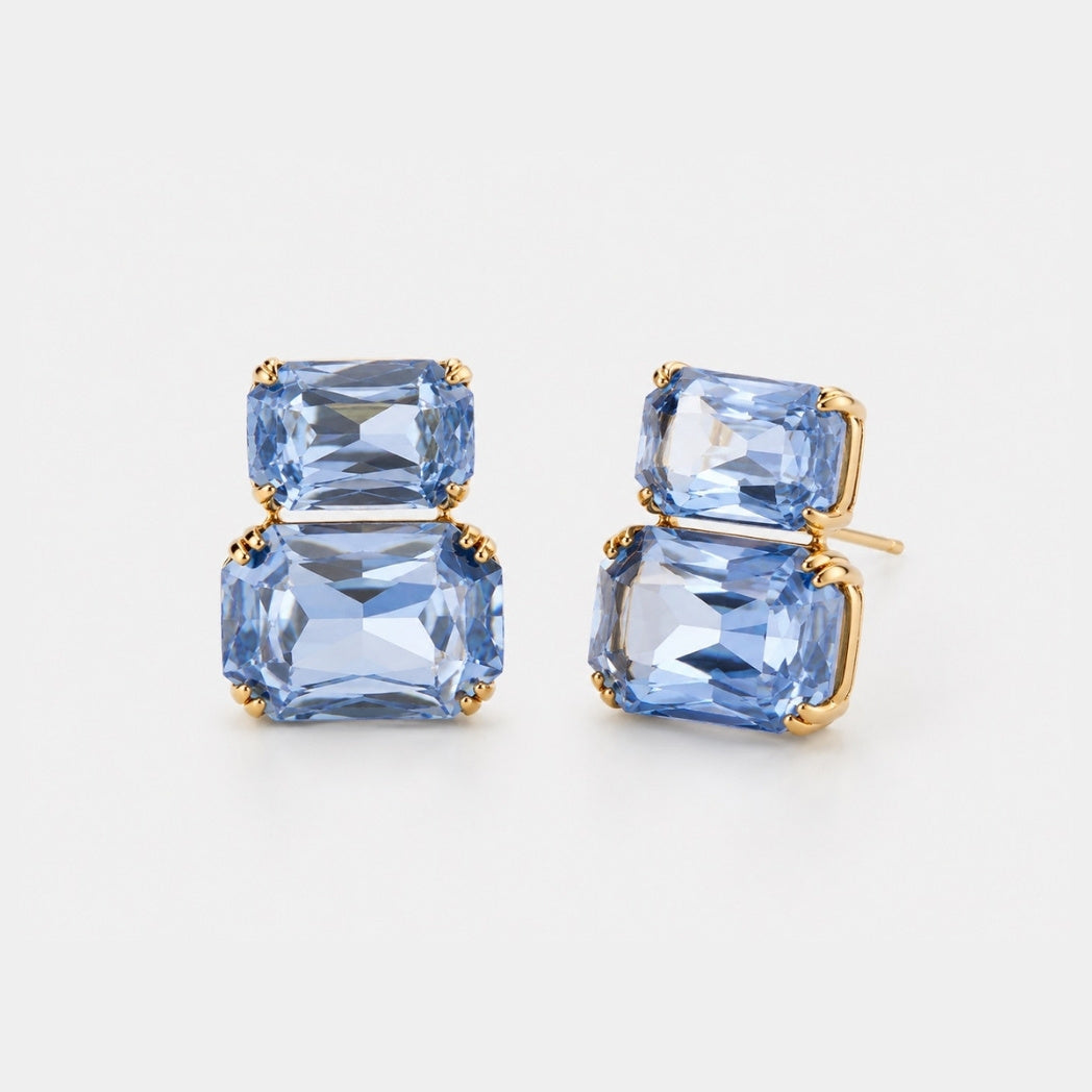 A pair of gold stud earrings featuring stacked rectangular light blue gemstones, shown on a clean white background.