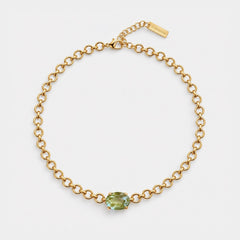 A gold chain necklace with a central oval-cut light green gemstone, displayed on a clean white background. A small gold tag on the clasp is engraved with the brand name 'SARABAI'.