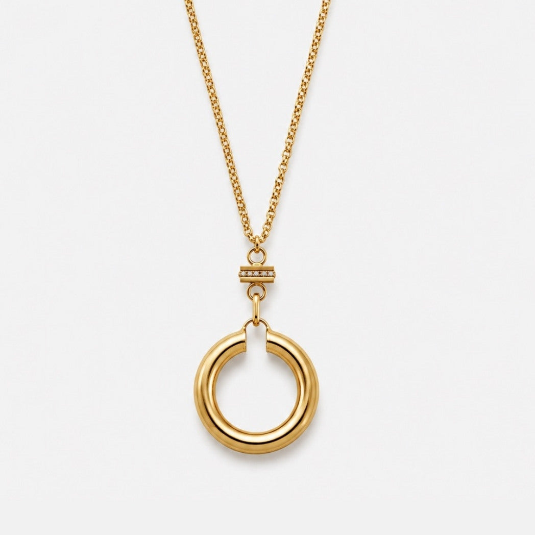 Gold necklace with a circular pendant on a white background