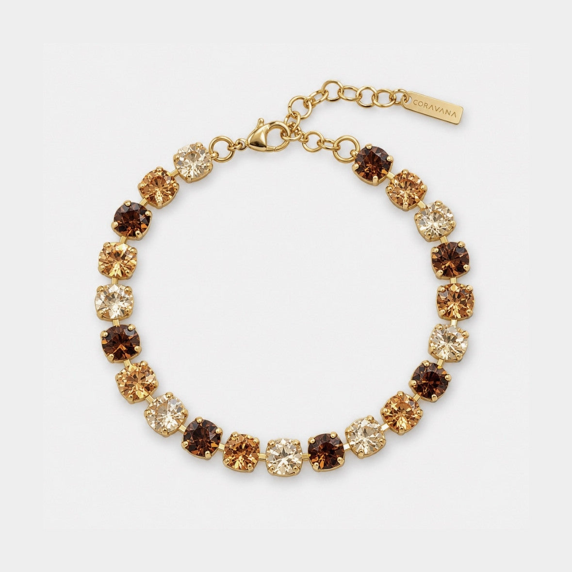 A gold-plated bracelet featuring alternating round clear, smoky brown, and champagne-colored rhinestones, displayed on a clean white background. A small gold tag on the clasp reads 'CROVATA'.