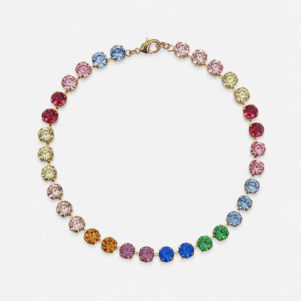 A gold-tone tennis necklace featuring a series of colorful round-cut rhinestones in a rainbow sequence, displayed on a clean white background.